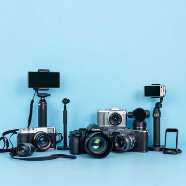 Digitalfotografie Verschiedene Kameras und Zubehör auf einem blauen Hintergrund angeordnet.
